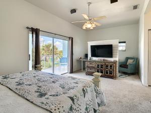 1 dormitorio con 1 cama y TV de pantalla plana en Salt Life Pool Home ~ Ocean Views ~ Walk to Flagler Avenue ~ 604S, en New Smyrna Beach