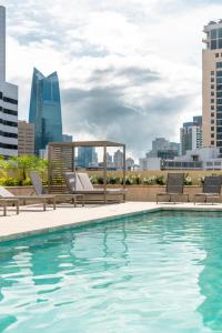 een zwembad met stoelen en een skyline van de stad op de achtergrond bij Waymore Hotel Spa & Casino in Panama-Stad