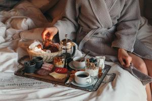 a person sitting on a bed with a tray of food at Ruka Peak - Boutique Hotel & Restaurant in Ruka