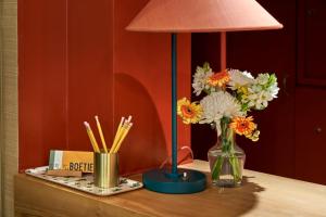 einen Tisch mit einer Lampe und einer Blumenvase in der Unterkunft Hôtel de La Boétie in Paris
