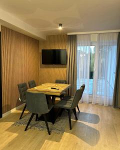 a dining room with a table and chairs and a television at Leśne Wzgórze Apartamenty in Korbielów