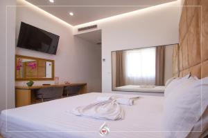um quarto com uma cama branca e uma televisão na parede em NBT Hotel Lac em Laç mais 18 fotografias