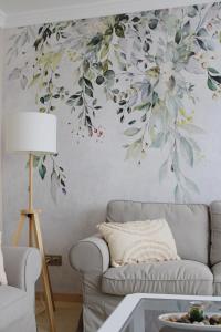 a living room with a couch and a wall with a flower mural at Córdoba Azahar in Córdoba