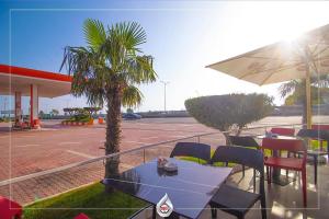 a patio with a table and umbrella and a parking lot at NBT Hotel Lac in Laç