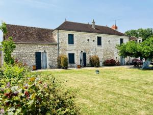 a large stone house with a grass yard at La Gouronerie in Parçay-sur-Vienne