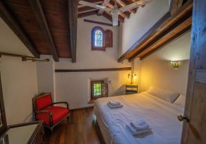 a bedroom with a bed and a red chair at Los Arbolitos Shared Housing in Güéjar-Sierra