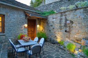 a patio with a table and chairs and a brick wall at Kipi Mountain Resort in Kipoi
