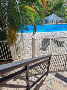 a fence with a bench in front of a pool at T2 cosy, spacieux et confortable in Les Trois-Îlets