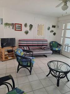 a living room with a couch and chairs and a tv at T2 cosy, spacieux et confortable in Les Trois-Îlets