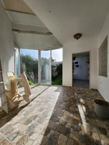 an empty room with a stone floor and large windows at Duplex bien equipe securise avec jardin et veranda in La Marsa