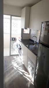 a kitchen with white cabinets and a sink and a refrigerator at FULLY RENOVATED APT BY THE OCEAN in Punta del Este