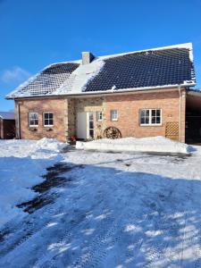 ein Backsteinhaus mit schwarzem Dach im Schnee in der Unterkunft Studio au coin des Fagnes in Sourbrodt