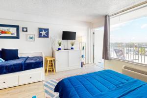 a bedroom with a blue bed and a balcony at Delights in Daytona Unit 525 in Daytona Beach