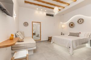 a white bedroom with a bed and a mirror at Porto Dema Luxury Suites in Schinoussa