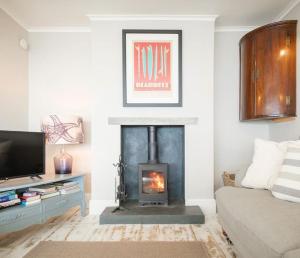 a living room with a fireplace and a couch at Mesmerising sea views - Penrose - above the beach Cornwall. in Downderry