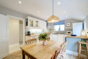 a kitchen and dining room with a wooden table at Mesmerising sea views - Penrose - above the beach Cornwall. in Downderry
