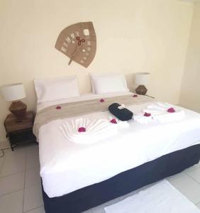 uma cama com lençóis brancos e rosas vermelhas em Wolfgramm Beachfront Motel em Utungake