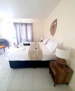 ein Schlafzimmer mit einem großen Bett und einer Lampe in der Unterkunft Wolfgramm Beachfront Motel in Utungake
