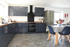 a kitchen with black cabinets and a table with chairs at Maen Llwyd in Llanyre