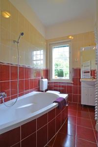 シオーフォクにあるSiófok Villaの赤いタイル張りのバスルーム(バスタブ付)、窓が備わります。
