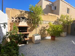 um pátio com vasos de árvores e um edifício em CASA TORRE Y MAR with 2 bedrooms swimming pool grill & garden & solarium em Torrevieja