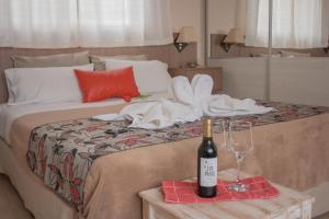 Una cama con una botella de vino y una copa en Mirador Serrano en Merlo