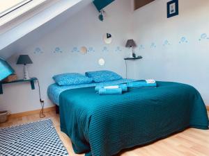 1 dormitorio con 1 cama con manta verde y almohadas azules en Le Gîte du Phare vue sur mer, en Cayeux-sur-Mer