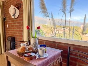 una mesa con desayuno y una ventana con vistas en Mirador Serrano en Merlo