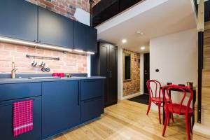 une cuisine avec des armoires bleues et des chaises rouges dans l'établissement Loft Black and Red, à Tallinn