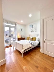 a bedroom with a white bed and a wooden floor at Holland House in New Brighton