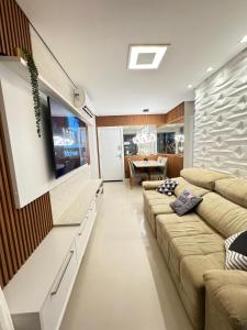 uma sala de estar com um sofá e uma televisão de ecrã plano em Edifício Maximus em Vila Velha