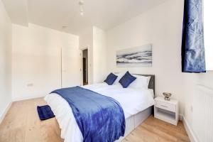 a white bedroom with a large bed with blue sheets at 2 Bedroom Apartment in Brixton with Wi-Fi in London