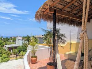 a patio with a straw umbrella and some plants at Penthouse -Sky at Mikasa- Fast wifi, King Bed, AC & Pool in Puerto Escondido
