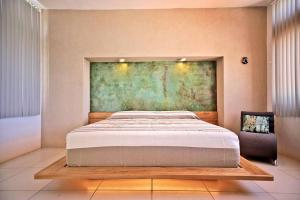 a bedroom with a large bed and a painting on the wall at Penthouse -Sky at Mikasa- Fast wifi, King Bed, AC & Pool in Puerto Escondido