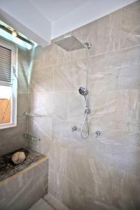 a bathroom with a shower with a stone wall at Penthouse -Sky at Mikasa- Fast wifi, King Bed, AC & Pool in Puerto Escondido
