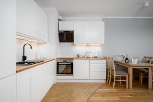 a kitchen with white cabinets and a wooden table at Apartments 24h in Warsaw