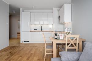 a kitchen with white cabinets and a table and chairs at Apartments 24h in Warsaw