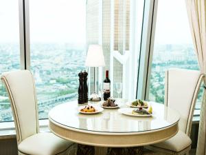 uma mesa com dois pratos de comida e vinho em frente a uma janela em Imperia City em Moscou