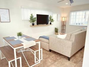 ein Wohnzimmer mit einer Couch, einem Tisch und einem Fernseher in der Unterkunft Historical Beach Bungalow Steps Away From Sand #5 in Newport Beach
