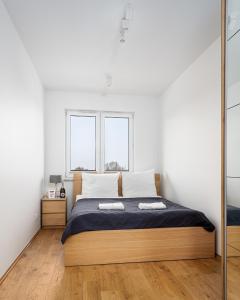 a bedroom with a bed and two windows at Apartments 24h in Warsaw