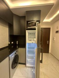 a kitchen with an open refrigerator and a microwave at cozy rooftop near al services 24 in Rujm ash Sharāʼirah
