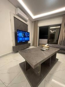 a living room with a table and a flat screen tv at cozy rooftop near al services 24 in Rujm ash Sharāʼirah