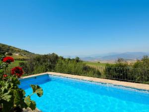拉霍亞的住宿－Belvilla by OYO Cortijo Los Olivos，蓝色的游泳池,带有围栏和山脉背景