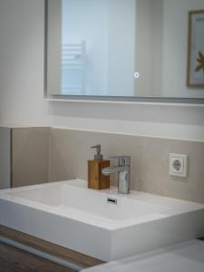 ein Waschbecken mit einem Wasserhahn und einem Spiegel in der Unterkunft Hochwertige Altbauwohnung im modernen Stil in Wiesbaden - Küche - Terrasse - WLAN - Zentral in Wiesbaden