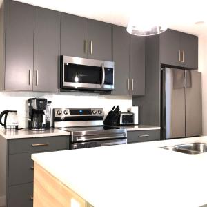 cocina con electrodomésticos de acero inoxidable y microondas en Mountain Retreat: Brand New 2BR Condo, en Canmore