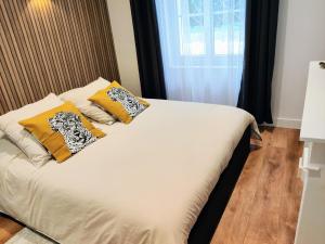 Un dormitorio con una cama con almohadas amarillas y una ventana en Confort & Style en plein coeur de Lisieux !, en Lisieux