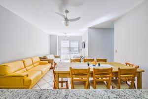 a living room with a yellow couch and a table and chairs at Confortável apto a 3min da praia de Mariscal CRA304 in Bombinhas