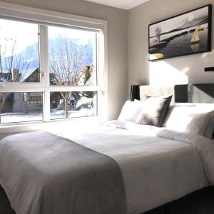 um quarto com uma cama branca e uma grande janela em Mountain Retreat: Brand New 2BR Condo em Canmore