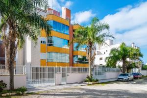 a building with palm trees in front of it at Confortável apto a 3min da praia de Mariscal CRA304 in Bombinhas