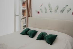 a white bed with two green pillows on it at Sunway Rome in Rome